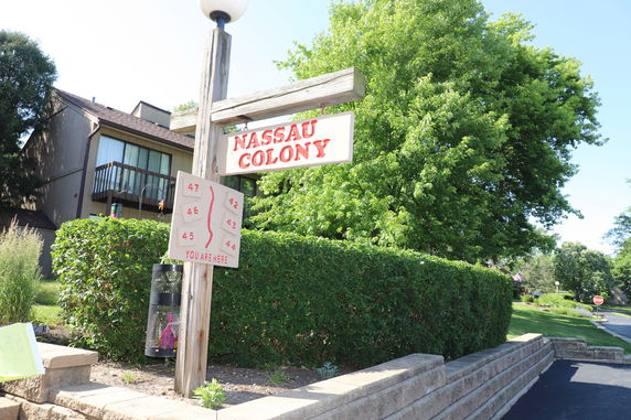 Front view of a row of residential buildings with a sign reading 'Nassau Colony'.