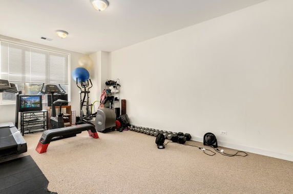 Room equipped with gym equipment including treadmill, exercise balls, and weights.
