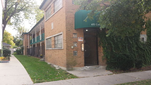 Front view of a multi-story brick building with a green awning over the entrance.