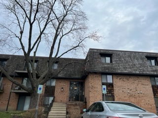 Front view of a three-story brick residential building with a gabled roof.