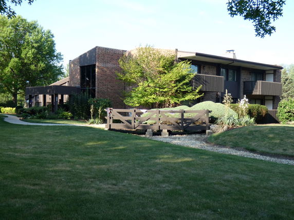 Front view of a two-story brick building with balconies and a wooden fence.