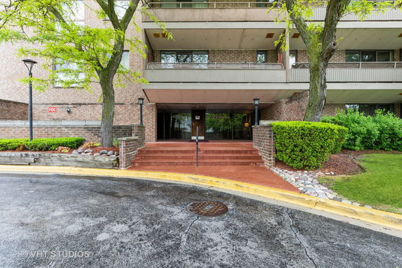 Front view of a multi-story brick building with a covered entrance and steps.