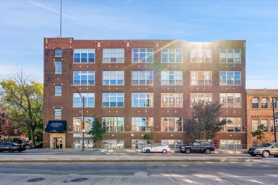 Front view of a multi-story brick building with large windows.