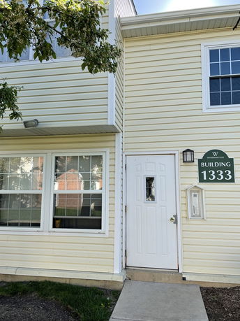 Front view of a building with a white door and large windows.
