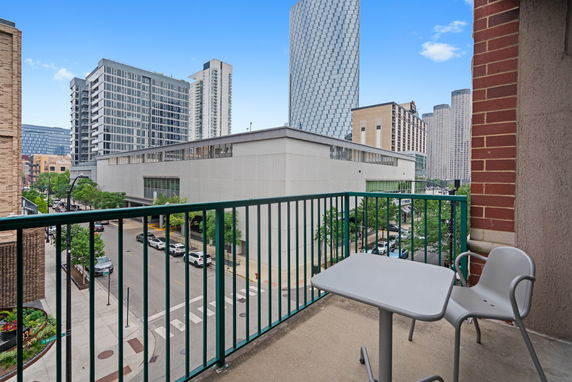 View of city buildings from a balcony with a table and chair.