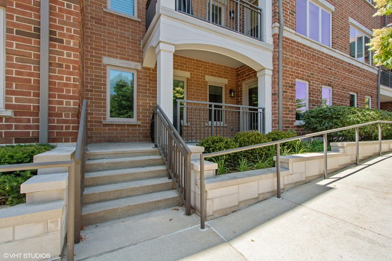 Front view of a multi-story brick building with stairs and a porch.