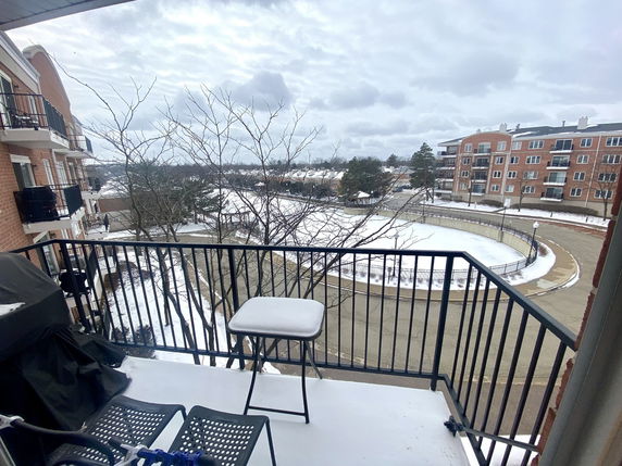 View from a balcony overlooking a snowy residential area with multi-story brick buildings.
