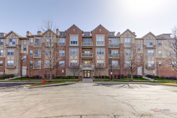 Front view of a multi-story brick building with balconies and large windows.
