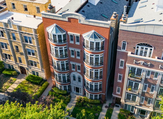 Front view of a multi-story brick apartment building with bay windows.