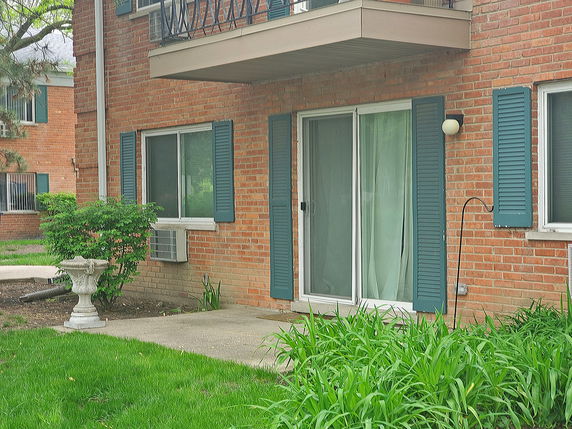 Brick exterior of a building with a patio and sliding glass door.