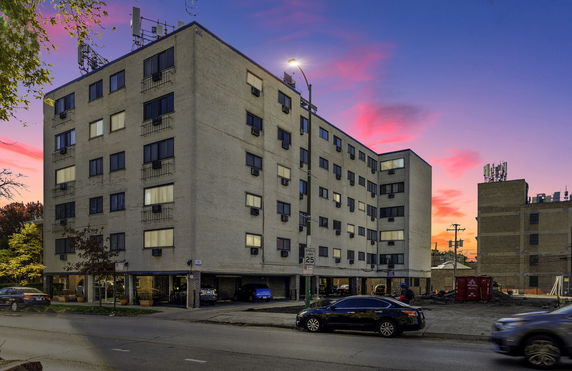 Front view of a multi-story apartment building with antennas on the rooftop.