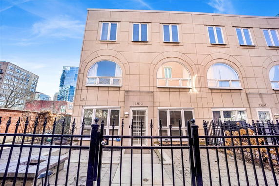 Front view of a three-story building with arched windows and a gated entrance.