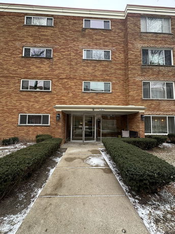 Front view of a multi-story brick apartment building with multiple windows.