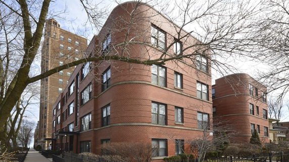 Front view of a multi-story brick building with rounded corners and multiple windows.