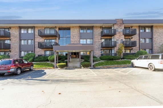 Front view of a multi-story brick apartment building with balconies.