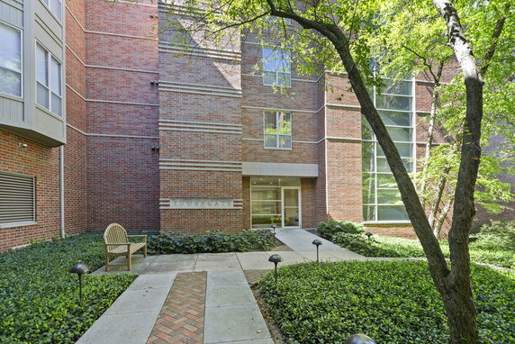 Front view of a brick building entrance with glass windows and a walkway.