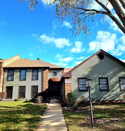 Front view of a two-story house with a gable roof and a mix of brick and siding exterior.