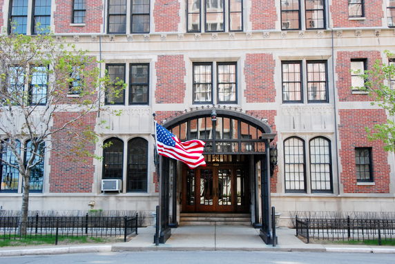Front view of a brick building with an American flag at the entrance.