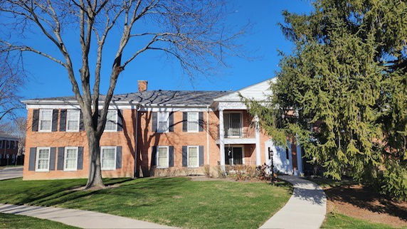 Front view of a two-story brick building with a central entrance and white trim.