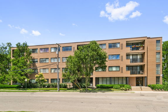 Front view of a multi-story apartment building with balconies and large windows.
