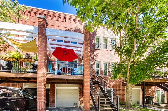 Front view of a multi-story brick building with a patio and staircase.