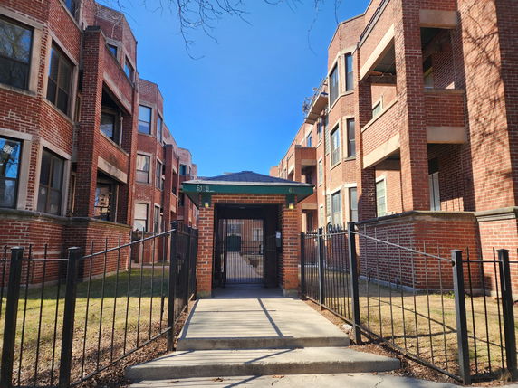Front view of a brick multi-story building with a gated entrance.