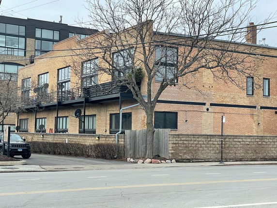 Front view of a multi-story brick building with large windows and a balcony.