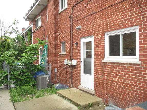 Side view of a brick two-story house with a white door and window.