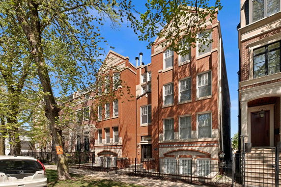 Front view of a multi-story brick building with windows and chimneys.