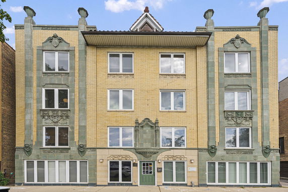 Front view of a multi-story building with decorative green trim and yellow brick facade.