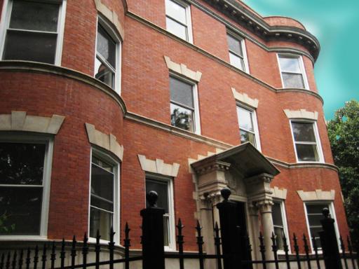 Front view of a three-story brick building with multiple windows and an ornate entrance.