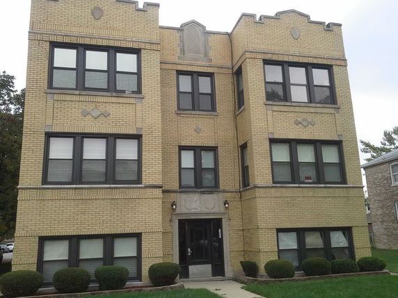 Front view of a three-story brick apartment building with multiple windows and a central entrance.