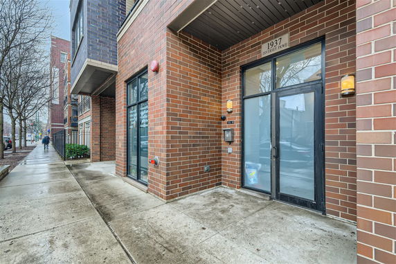 Front view of a brick building entrance with large glass doors.