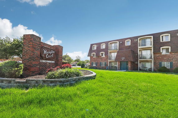 Front view of a multi-story brick condominium building with balconies.