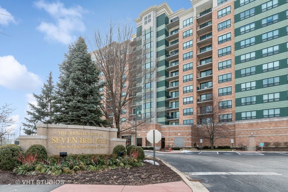 Front view of a multi-story residential building with a parking area.