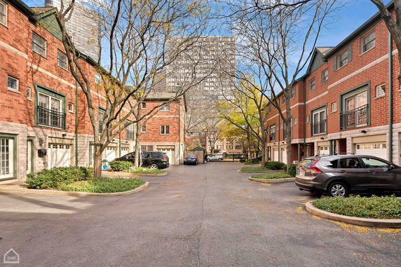 Outdoor parking area surrounded by brick buildings with garages.