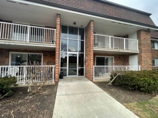Front view of a two-story brick building with balconies and a central entrance.
