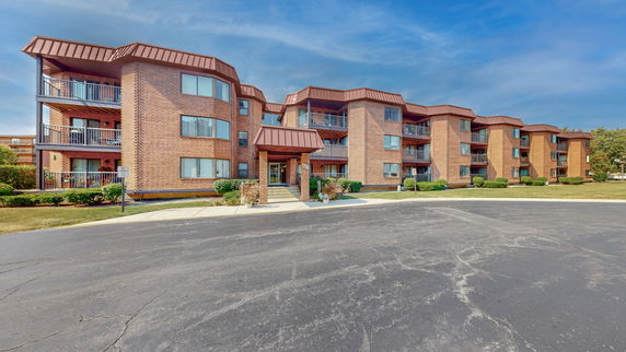 Front view of a multi-story brick apartment building with balconies