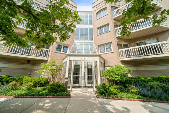 Front view of a multi-story residential building with balconies and a glass entrance.