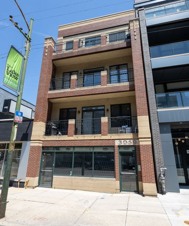 Front view of a multi-story building with balconies and a ground-floor entrance.