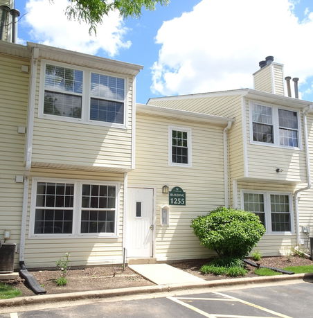Front view of a two-story house with yellow siding and multiple windows.