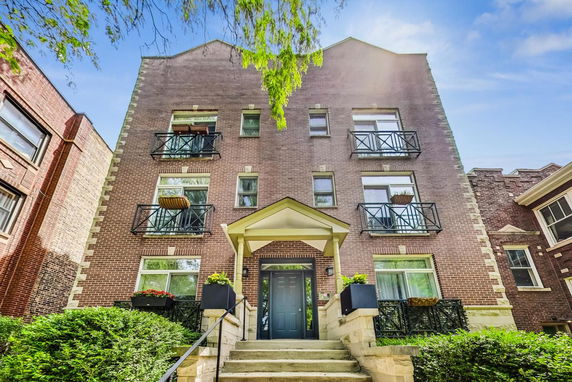 Front view of a multi-story brick building with balconies and an entrance canopy.
