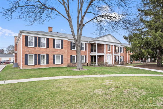 Front view of a two-story brick apartment building with black shutters.