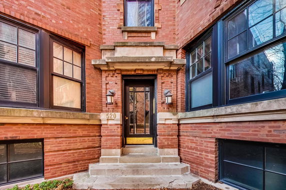 Front view of a brick house with an entrance door and steps.