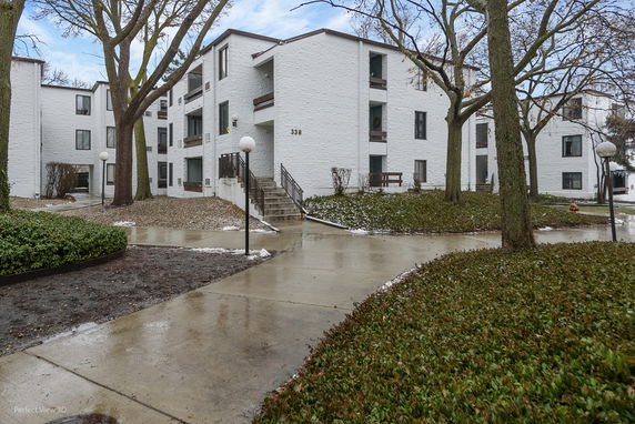 Front view of a multi-story residential building with white brick exterior.