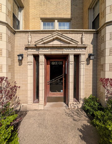 Front view of a brick building entrance with decorative elements.