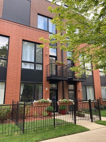 Front view of a multi-story brick building with balconies and large windows.