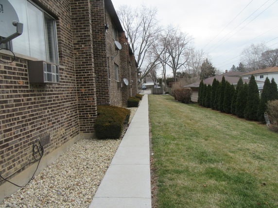 Side view of a brick building with multiple satellite dishes and air conditioning units.