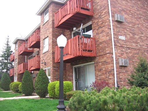 Front view of a three-story brick apartment building with balconies.