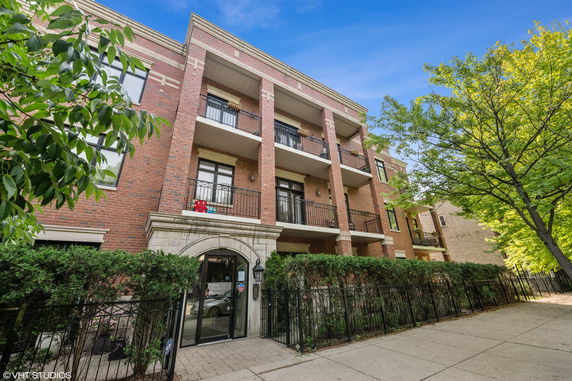 Front view of a three-story brick building with balconies.